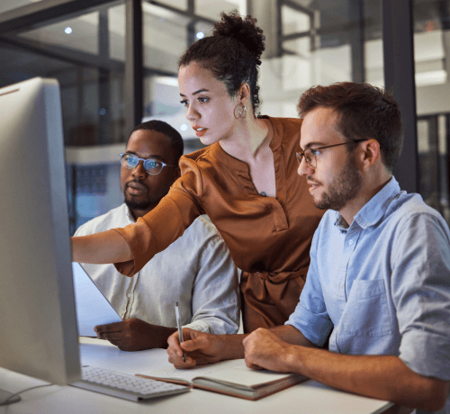 Colleagues collaborating at a monitor in a modern office, representing integrated delivery streams and shared visibility